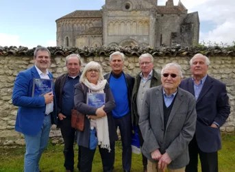 Élus et partenaires réunis devant une église romane de Charente-Maritime