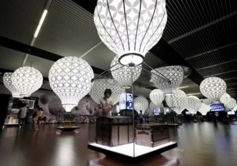 Exposition Louis Vuitton Voyages : lanternes lumineuses suspendues au-dessus des vitrines