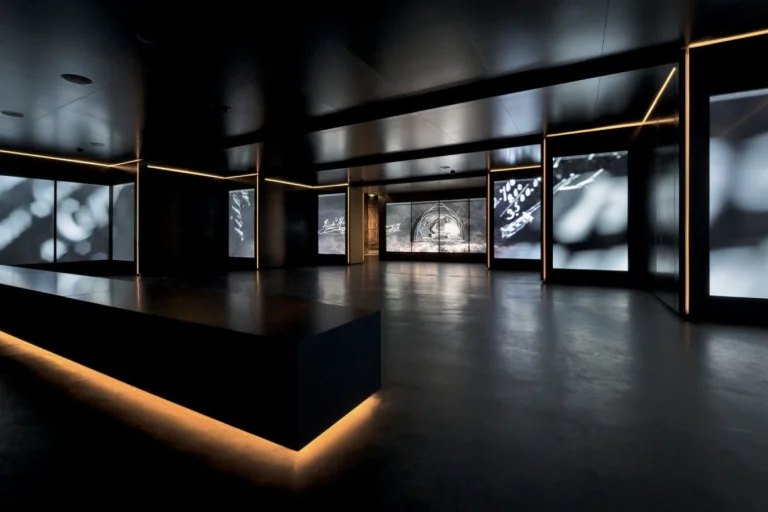 Parcours d'exposition immersif : vitrines rétroéclairées dans une salle sombre